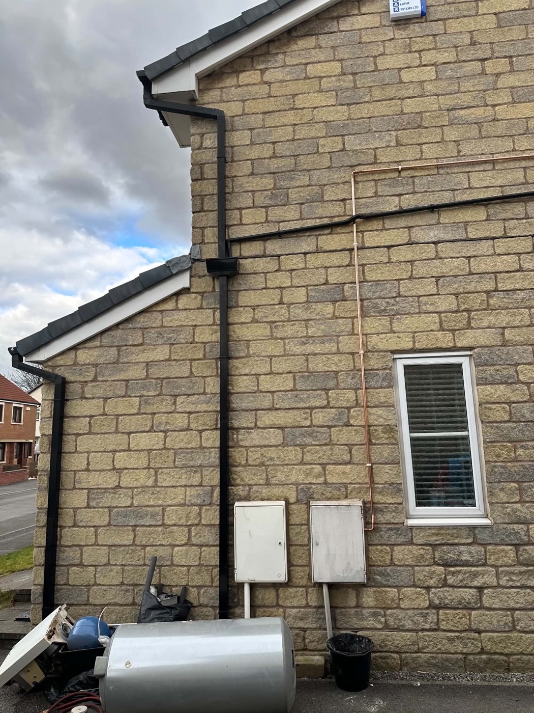 External copper pipework running along a stone house wall